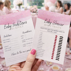 Hand holding baby shower game cards with pink and white design, blurred background of a party.