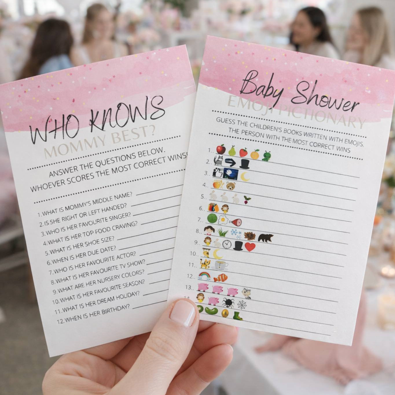 Two baby shower game cards held by a hand with a blurred background of a baby shower.